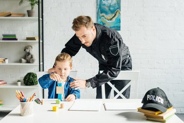 young father in police uniform and son playing together at home