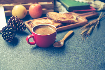 Breakfast scene with coffee cup, bread and fruits on the table. Vintage tone