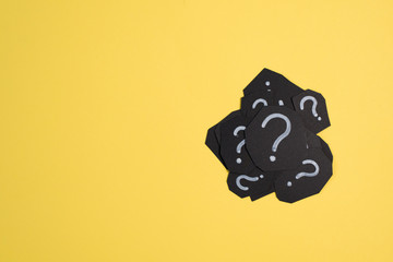 heap of black paper card with QUESTION MARK on bright yellow background. Concept of FAQ, Q&A,...