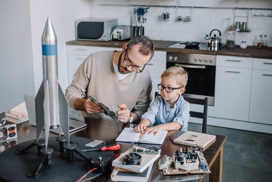 father and son repairing microcircuit at home