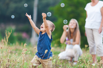 Happy child with family having a great time blowing bubbles - Powered by Adobe
