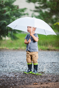Adorable child holding an umbrella in a rain storm