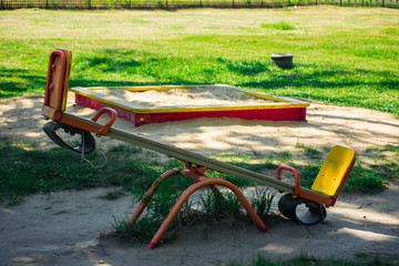 Empty children's swing with a sandbox in the background. A modern children's playground for children in the city park