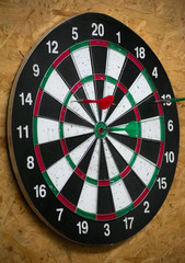 Classic darts board with two green and red small pointed missiles with plastic flights