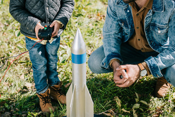 cropped shot of father and little son launching model rocket outdoor