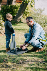 side view of father and little son launching model rocket outdoor