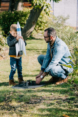 father and son playing with model rocket together at sunny day