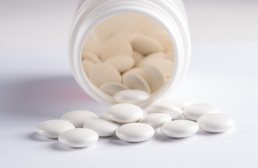 White round tablets covered with a cover are scattered from a plastic can with themWhite round tablets covered with a cover are scattered from a plastic can with them