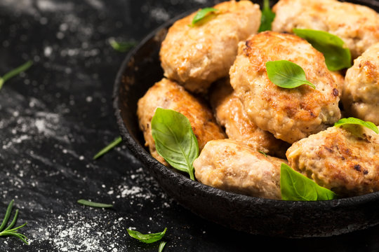 Homemade chicken cutlets in a pan. Dark background with copy space
