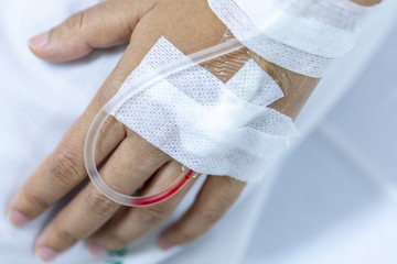 Close up hand woman patient with injection Saline in hand and during lying rehabilitation beds the hospital.