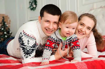Happy smiling family with one year son near the Christmas background