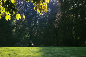 Man enjoys the sun while reading a book in the park