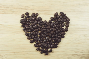 coffee beans in shape of heart on wooden background