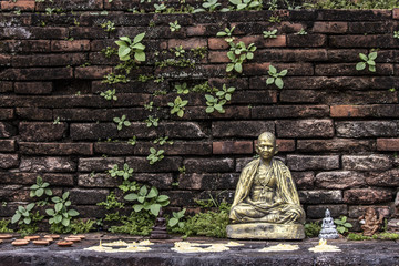 Bronze statue of Buddha on classic textured brick wall