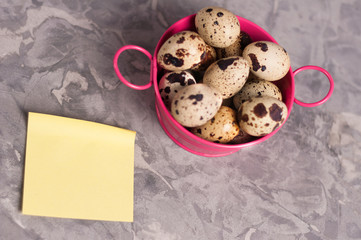 One pink metal rural basin with handles full of spotted fresh quail eggs and yellow curved blank...