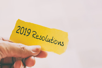 Hands holding piece of paper with text - 2019 Resolutions.
