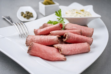 Traditionelle bayrische Brotzeit mit Rostbraten und Remoulade als closeup auf einem weißen Teller