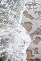 Unusual and very beautiful sea foam on the background of a sandy clean beach on a bright and sunny summer day