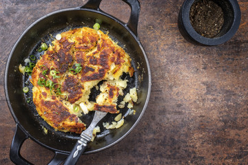 Traditional Swiss rosti as side dish with leek as top view in a frying pan with copy space right