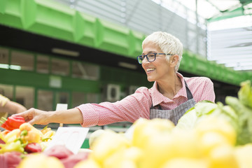 Senior woman sells vegetable on market