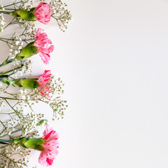 Pink carnations and white field flowers on white copy space background