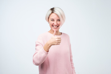 Portrait of beautiful woman with dyed short hair with thumbs up sign