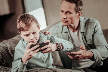Listen to me. Handsome male person actively gesticulating while talking to his son