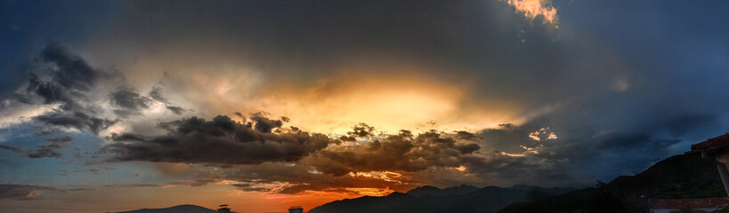 The setting sun, hiding in the dark clouds above the horizon, illuminates everything around with the last rays.
