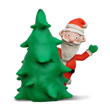 Weihnachtsmann aus Knete schaut winkend hinter einem Tannenbaum hervor