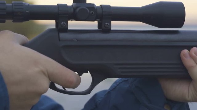 A black hunting rifle with a telescopic sight mounted on rifle shooting rest on firing range on a bright autumn day, close-up
