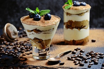 Classic Tiramisu dessert in a glass isolated on dark background