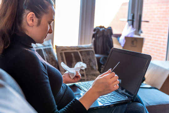 young sick woman at home paying for mdeicines on laptop next to medicines - Powered by Adobe