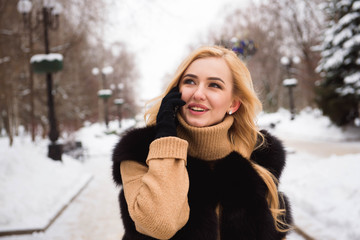 Outdoor close up photo of young beautiful happy smiling girl walking on street in winter.
