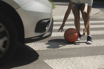 Close-up on kid with ball on pedestrian crossing next to car