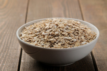 Dry oatmeal in a white bowl. food. healthy food. on a brown wooden table