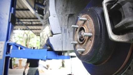 corrugation vehicle's exhaust system at shallow depth of field and Disc brake of the vehicle for repair, in process of new tire replacement. Car brake repairing in garage.Close up.