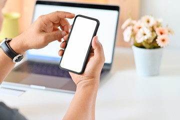 Male hands holding mobile phone in office.
