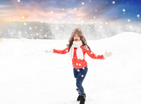 people, season and leisure concept - happy woman in fur hat having fun outdoors over natural winter background and snow