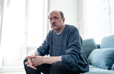 Sad unhappy old senior man suffering from memory loss and alzheimer feeling depressed and lonely