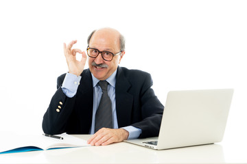 Pleased mature business man in his 60s working on laptop confident of success