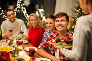 holidays and celebration concept - happy friends having christmas dinner at home