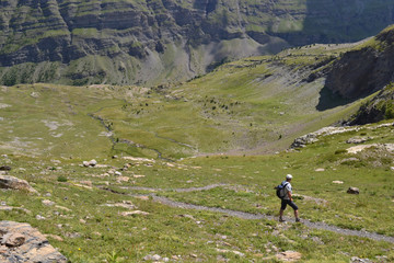 Fototapeta na wymiar Randonneur avec une casquette blanche et un sac à dos sur le sentier de Dormillouse dans les Hautes-Alpes, Parc National des Ecrins, Alpes, France