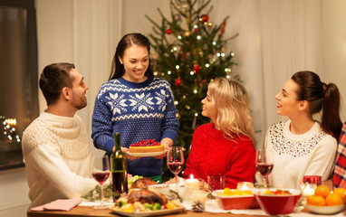 holidays and celebration concept - happy friends having christmas dinner at home