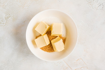 Dough cooking - white and brown sugar, pieces of butter in bowl, top view