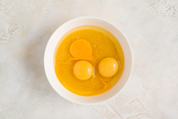 Dough cooking - eggs adding in a white bowl with mix of sugar and butter, top view