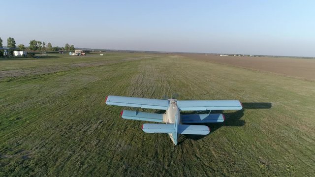 old propelled airplane takes off over field against sky and horizon line in spring in Top view