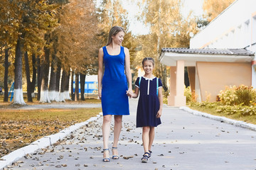 Young mother picks up little daughter after lessons in school. Parenthood concept.