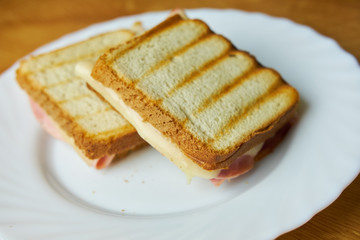 Tasty ham and cheese toast on white plate