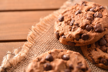 Chocolate cookies on sackcloth on wooden slatted table detail