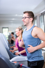 junge, hübsche Frau trainiert im Fitnessstudio auf dem Laufband laufen.